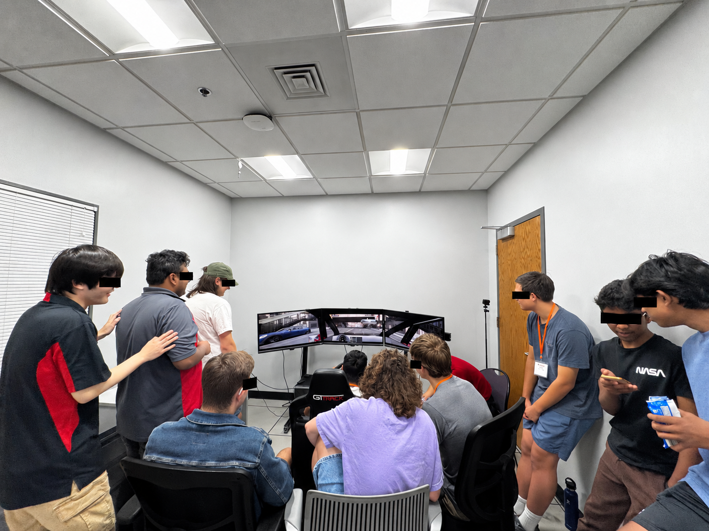 High school students gather around the MINDxAI Lab driving simulator during the 2025 ISE Summer Camp.