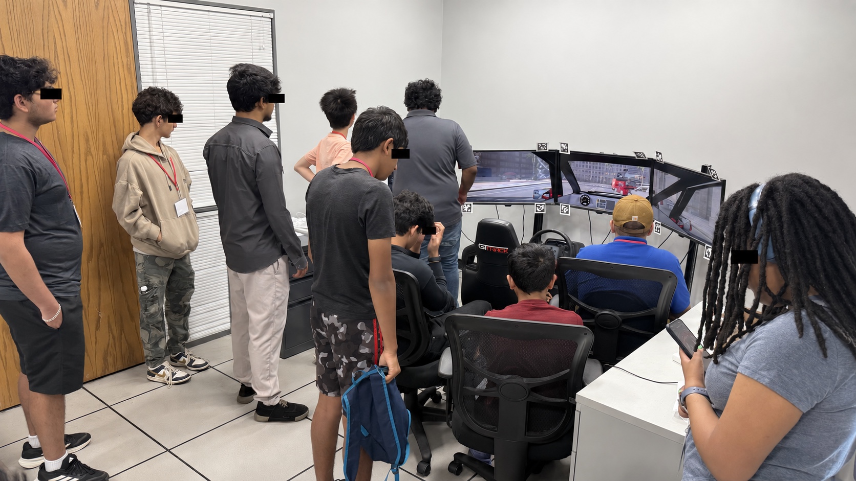 Students observe the driving simulator during the July 2026 Design Thinkers Camp, with visible eyes covered for privacy.