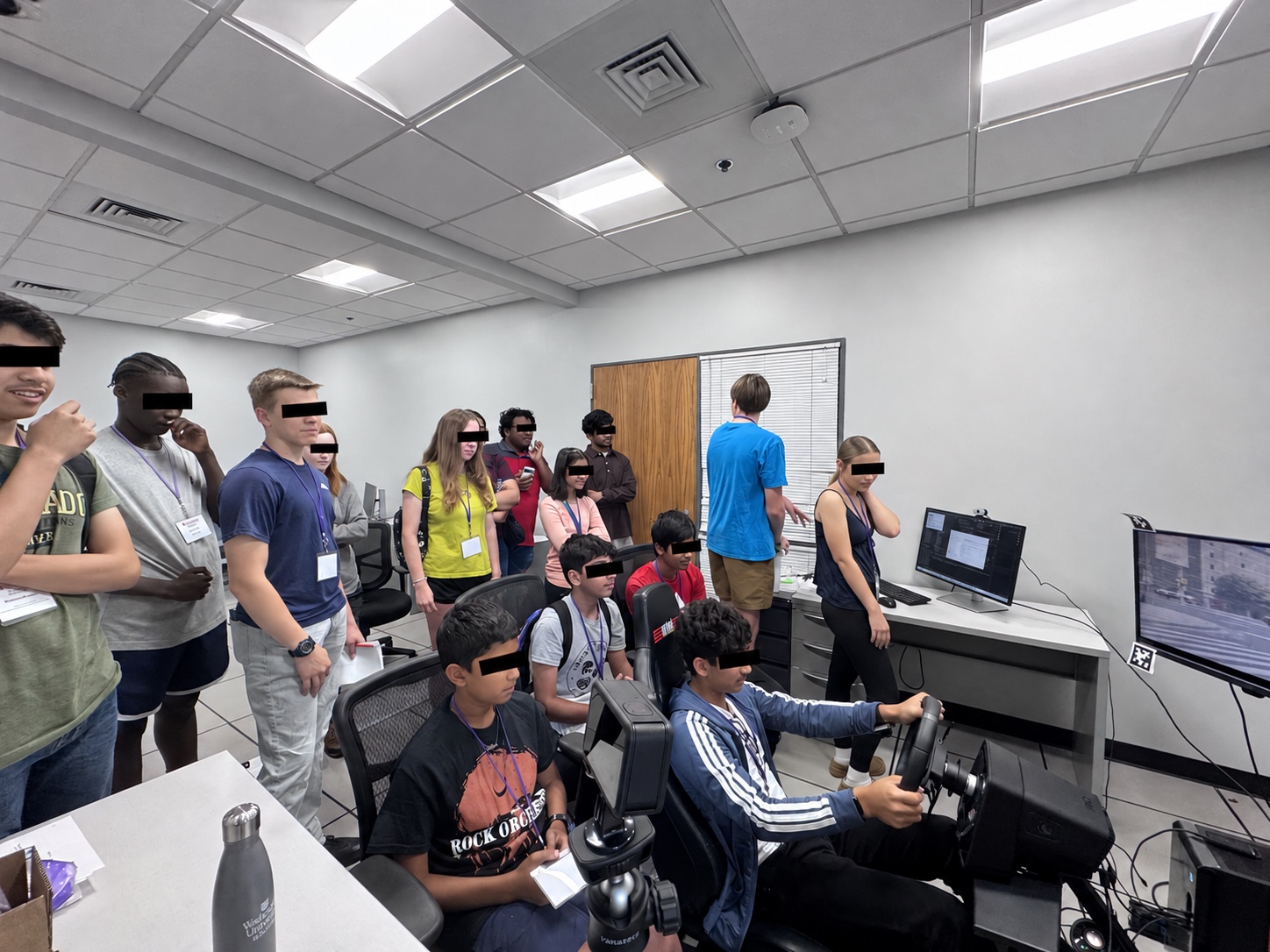 Students take part in the MINDxAI Lab driving simulator session at the June 25, 2026 ISE Summer Camp, with eyes covered for privacy.